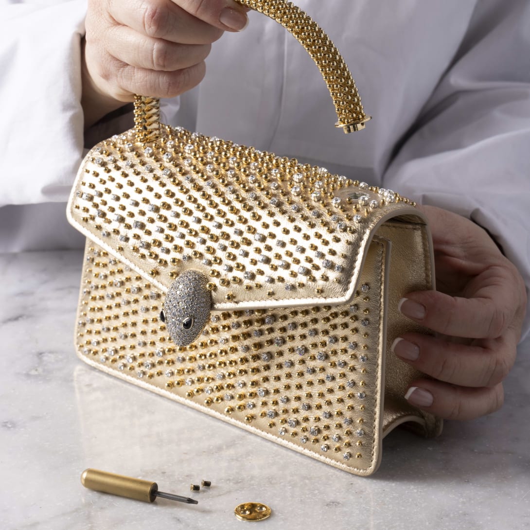Bvlgari artisan assembling the snakehead closure of the Serpenti Cabochon quilted bag, close-up.