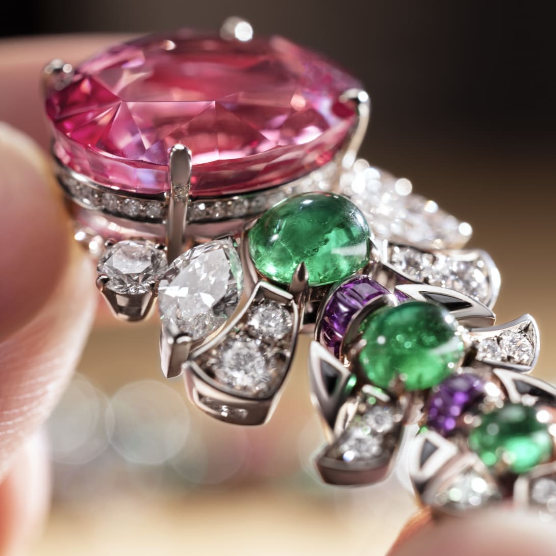 Bvlgari artisan mounting an emerald on a necklace and a sketch of a jewel, close-up on the hands.