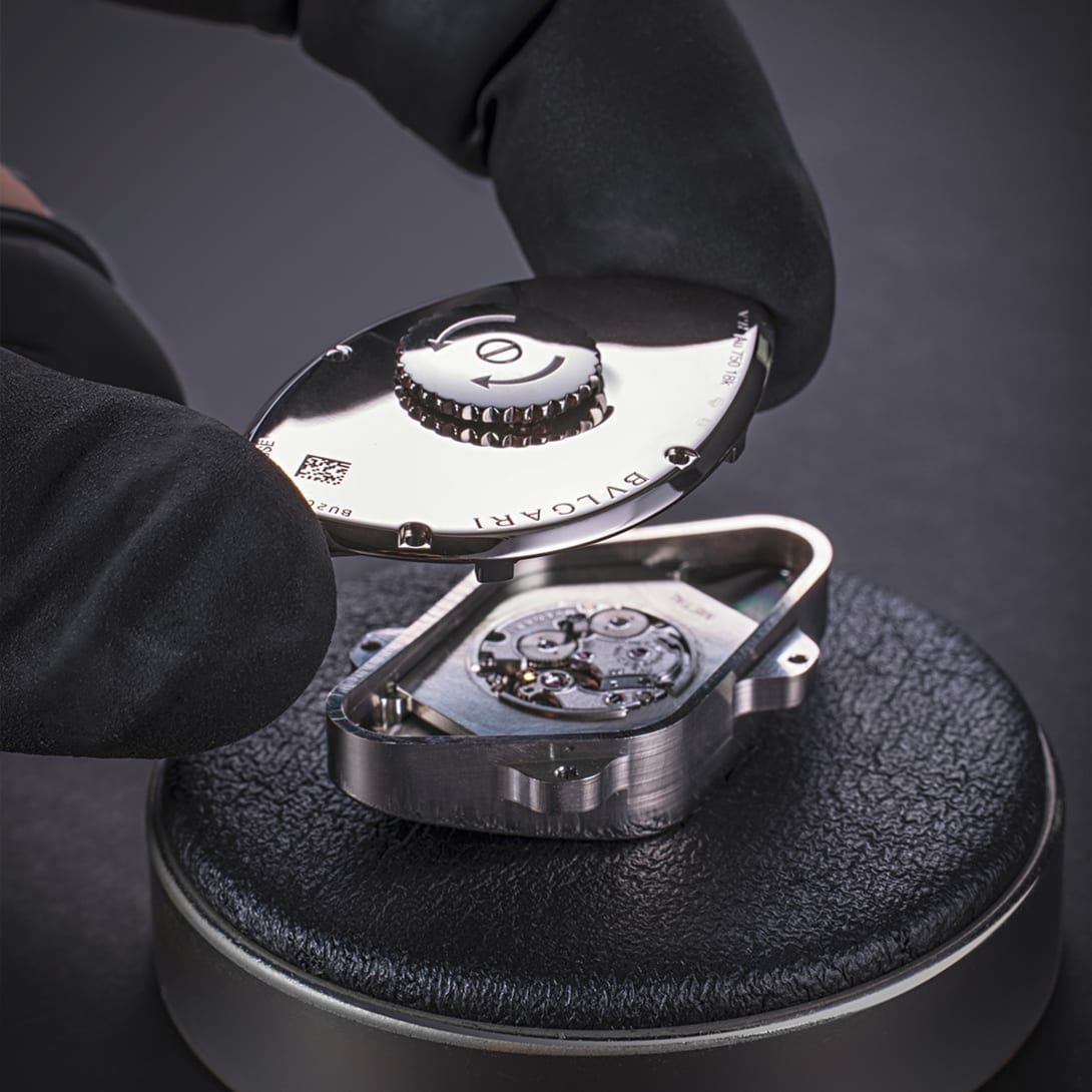 Bvlgari watchmaker assembling a mechanical manufacture calibre with black gloves, close-up.