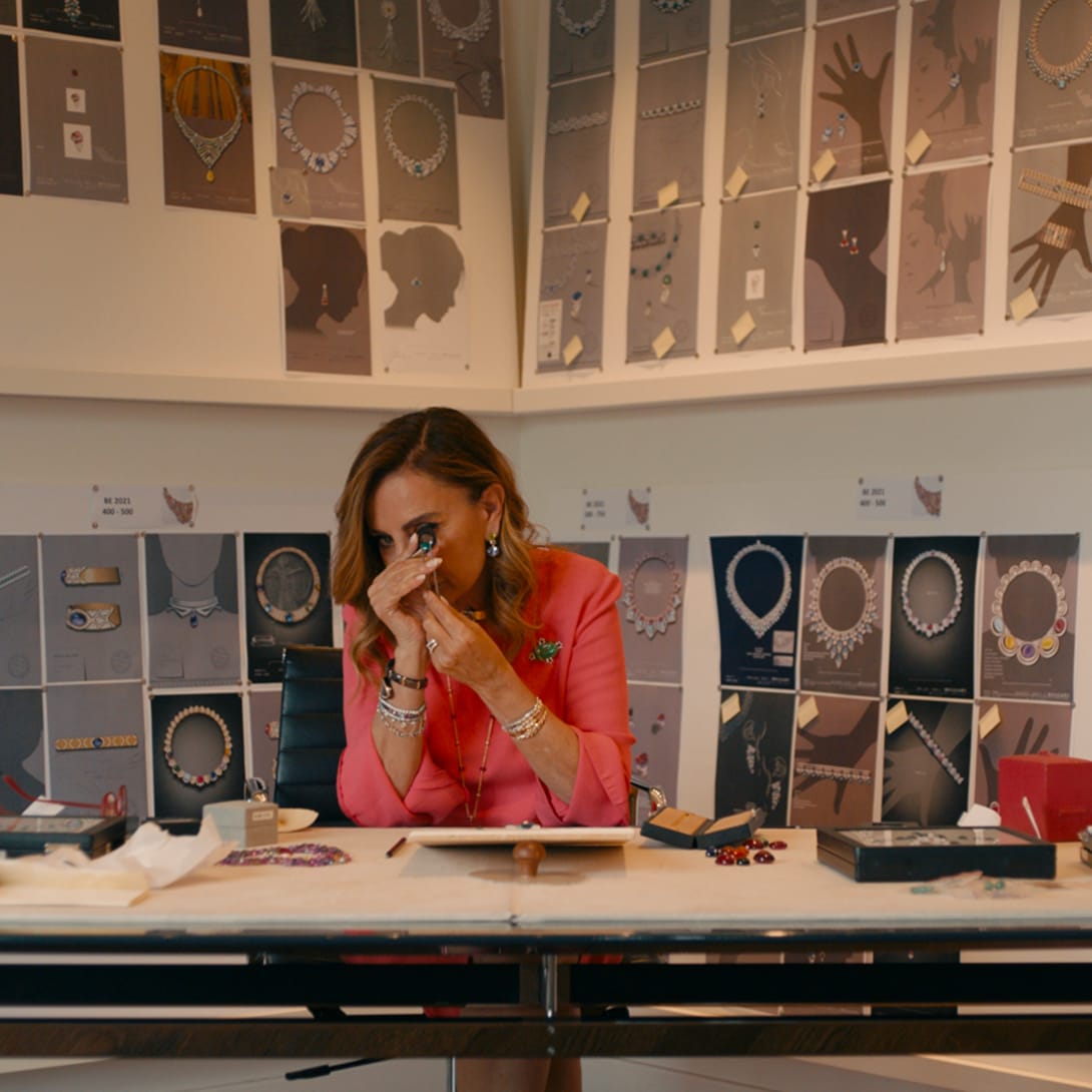 Bvlgari's Jewellery Creative Director Lucia Silvestri analysing a gem, jewellery sketches in the back.