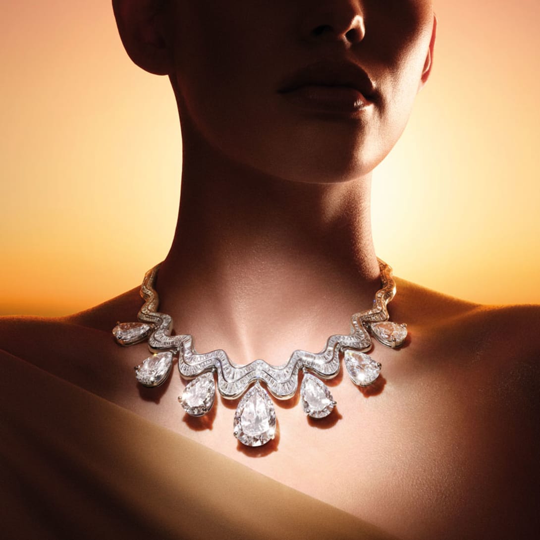 Model wearing the Serpenti Aeterna High Jewellery necklace with seven diamond drops, sky at dawn.