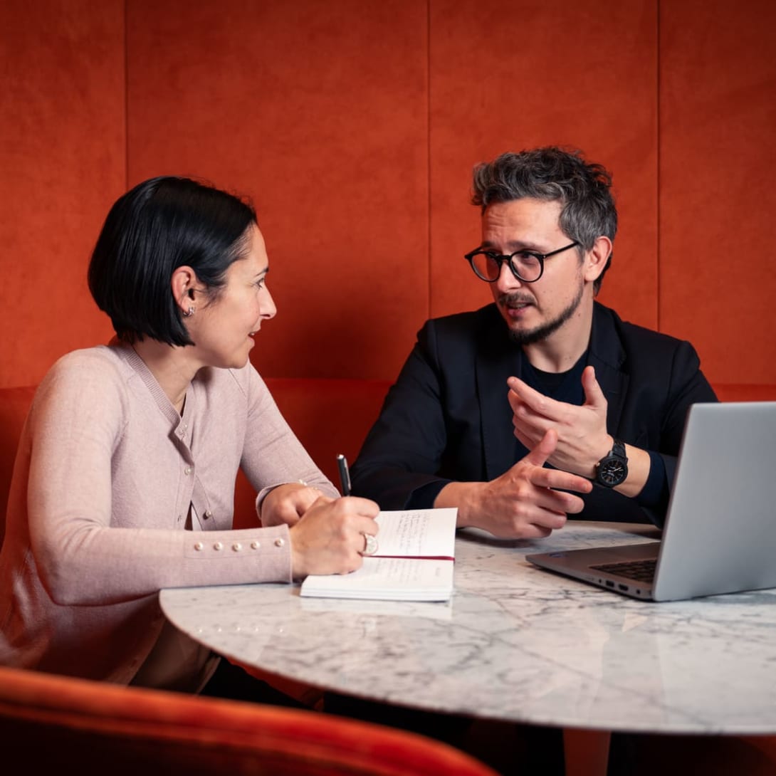 Nicola, Data Domain Manager at Bulgari, and a colleague chat while working together in front of a computer