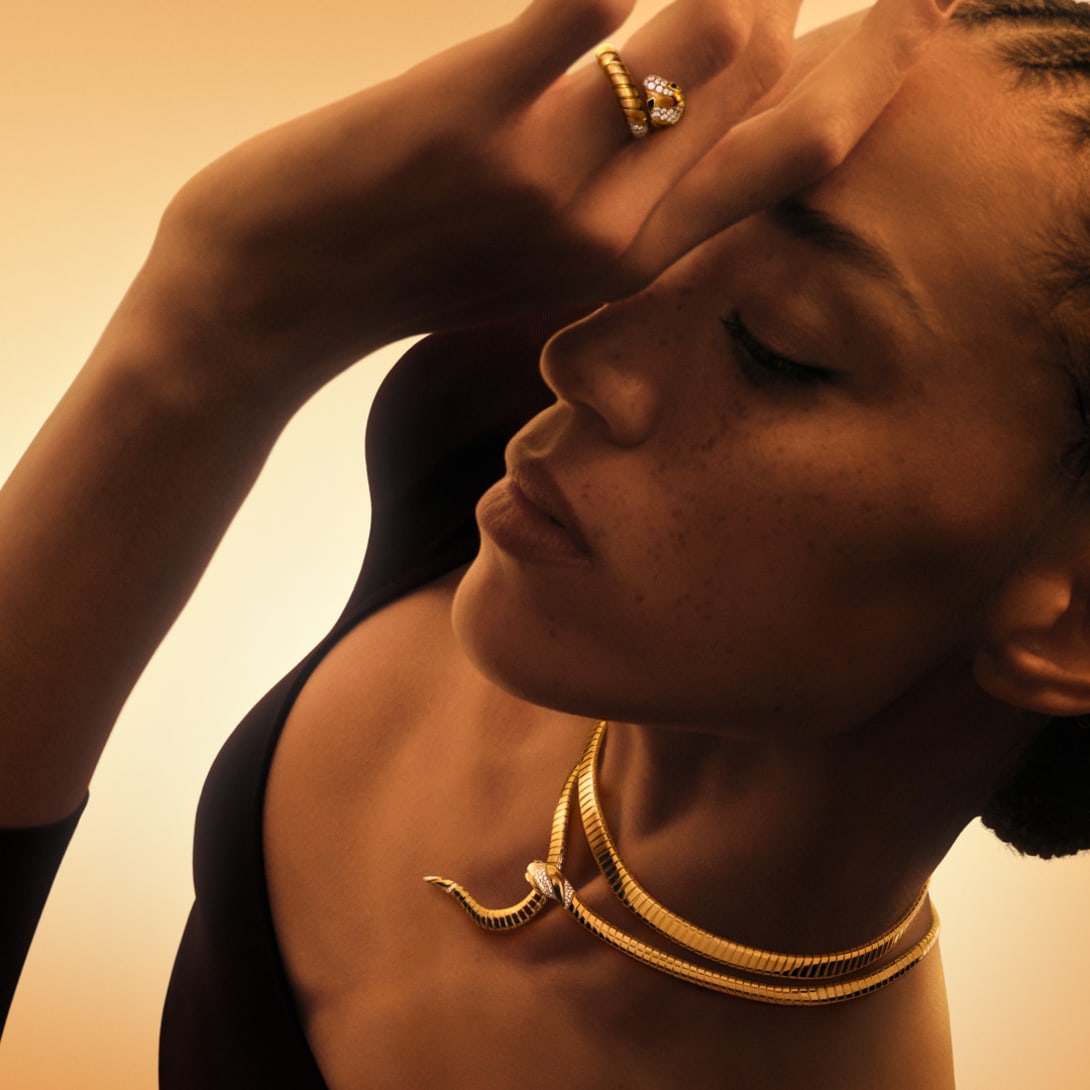 Model wearing Serpenti yellow gold necklace and ring with Tubogas body and set with diamonds, close up.