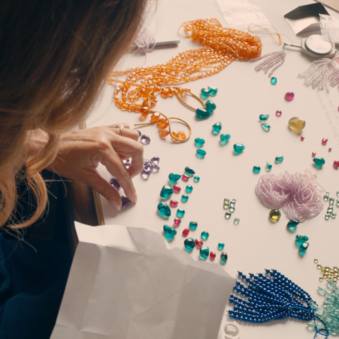 Lucia Silvestri creating a layout of coloured gems on her gem table, close-up.