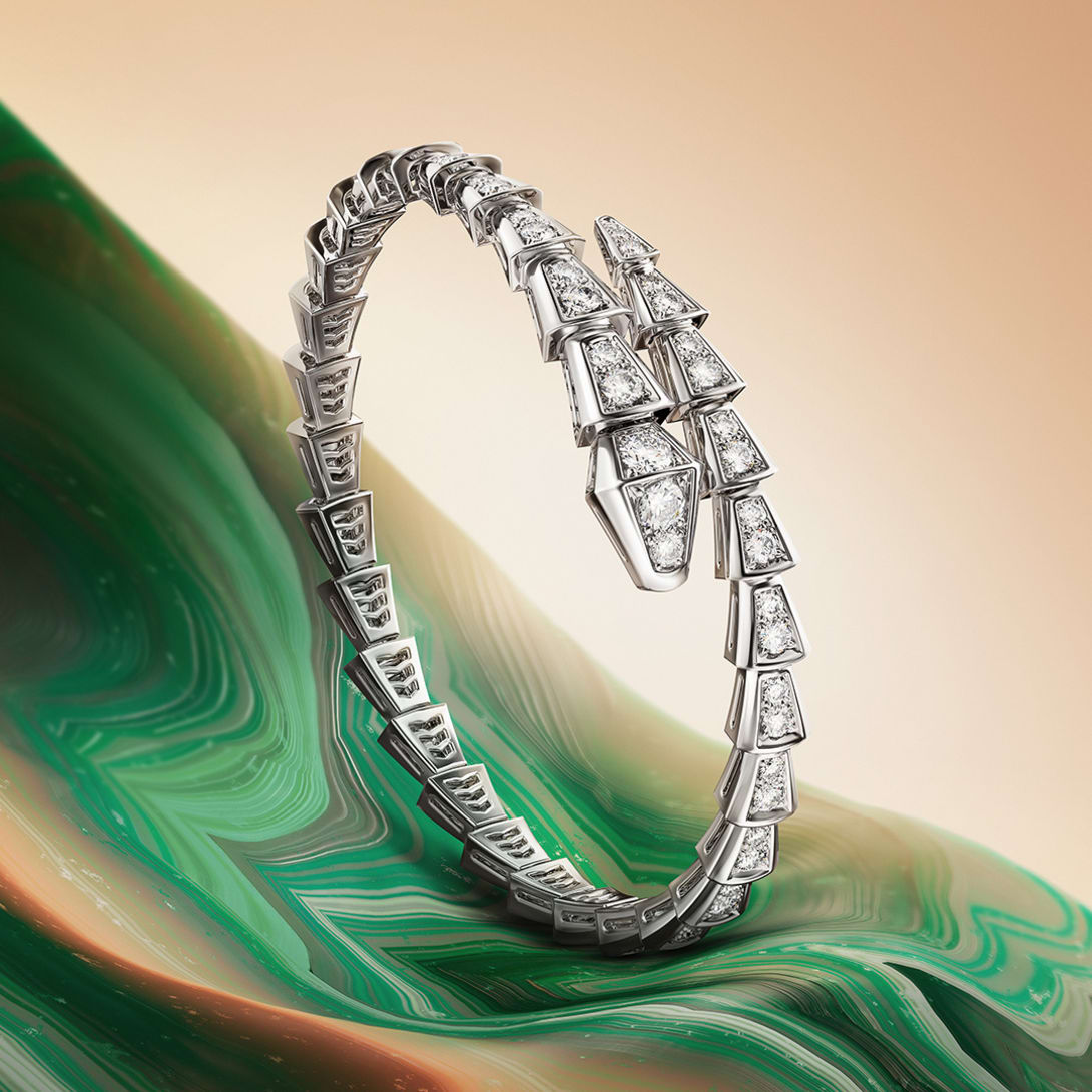 Serpenti Viper single coil bracelet in white gold with diamonds, green and beige creative backdrop.