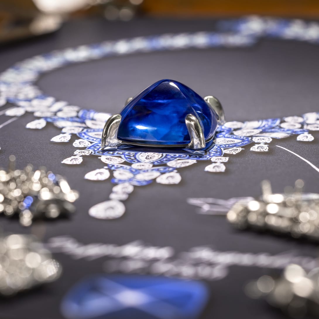 Bvlgari artisan mounting an emerald on a necklace and a sketch of a jewel, close-up on the hands.