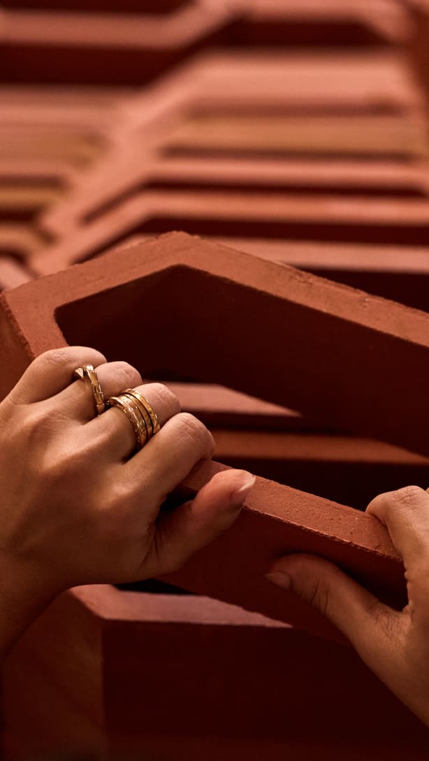 Hands touching a terracotta element from Doyel Joshi’s Passing The Light installation for Bvlgari.