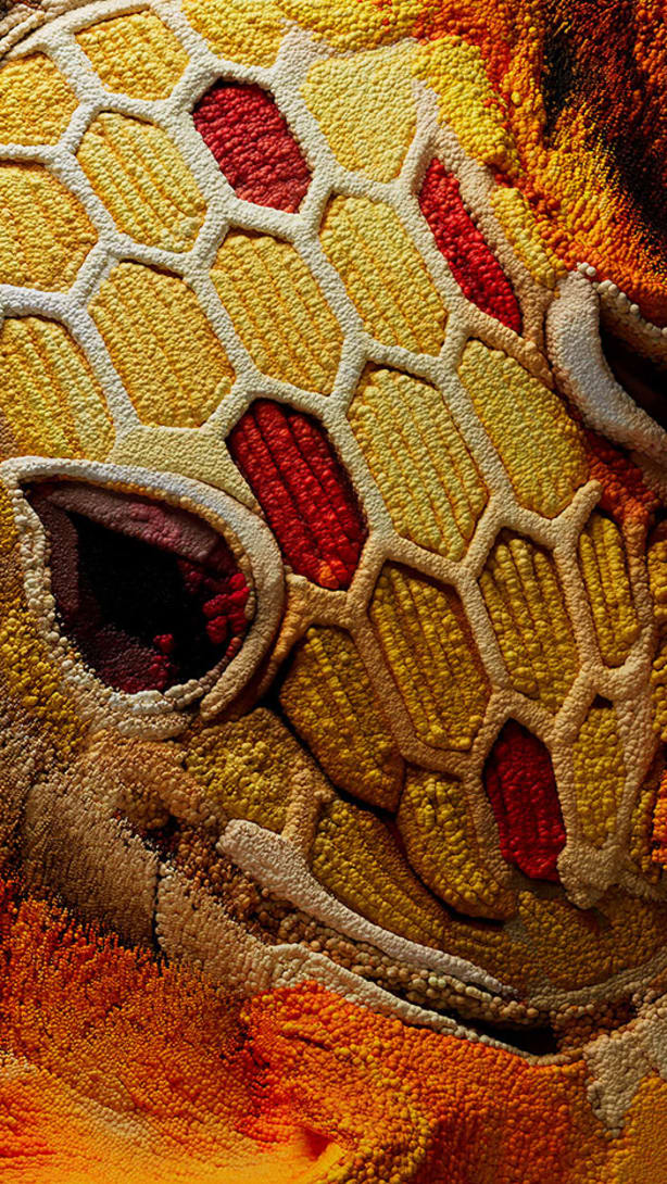 Serpenti Heritage bracelet in yellow gold with red and yellow enamel and red gemstone eyes, close up.