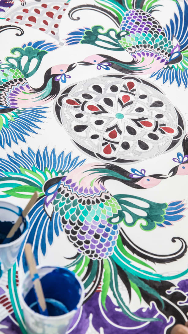 Hand paints a drawing of a Bvlgari Serpenti bag.