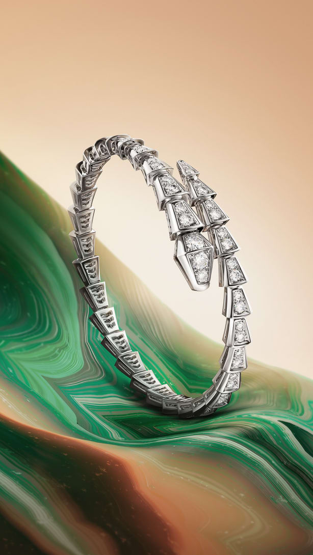 Serpenti Viper single coil bracelet in white gold with diamonds, green and beige creative backdrop.