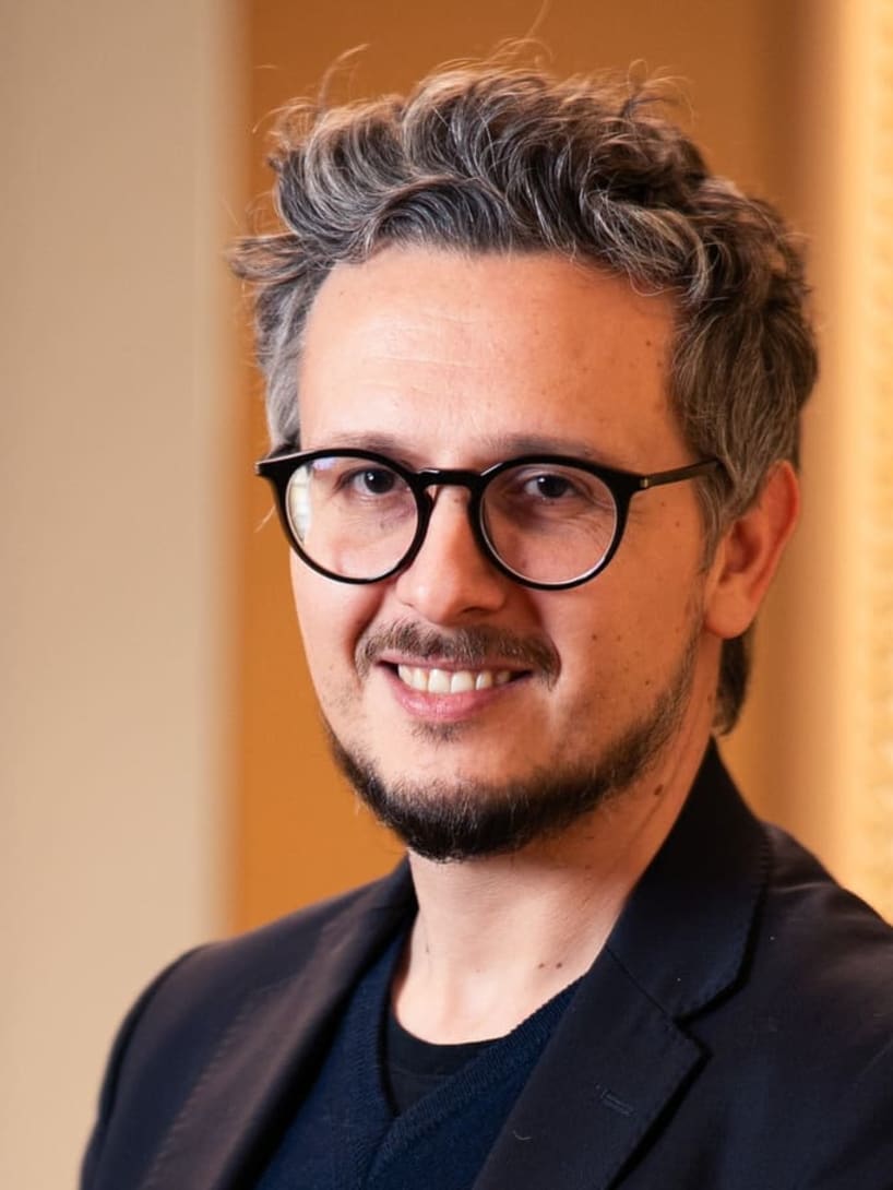 Nicola, responsable de dominio de datos en Bvlgari, apoyado en la pared sonriendo