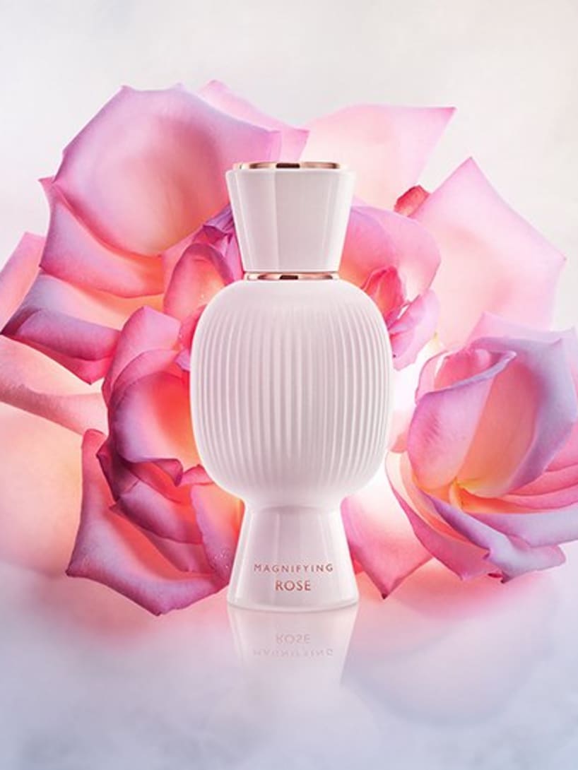 White flacon of the Bvlgari Allegra Magnifying Rose essence in front of a pink rose, creative shot.