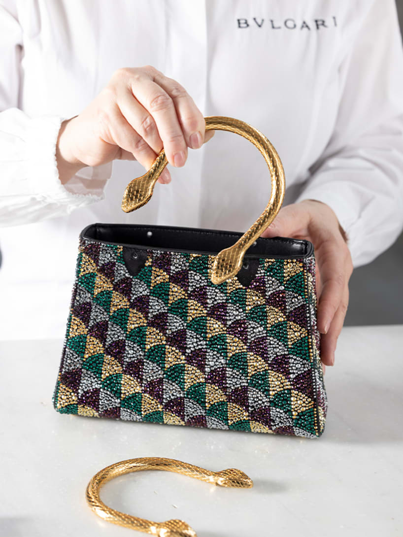 Craftsman assembling the snake-body shaped handle of the Serpentine Duo tote bag with Calla crystals.