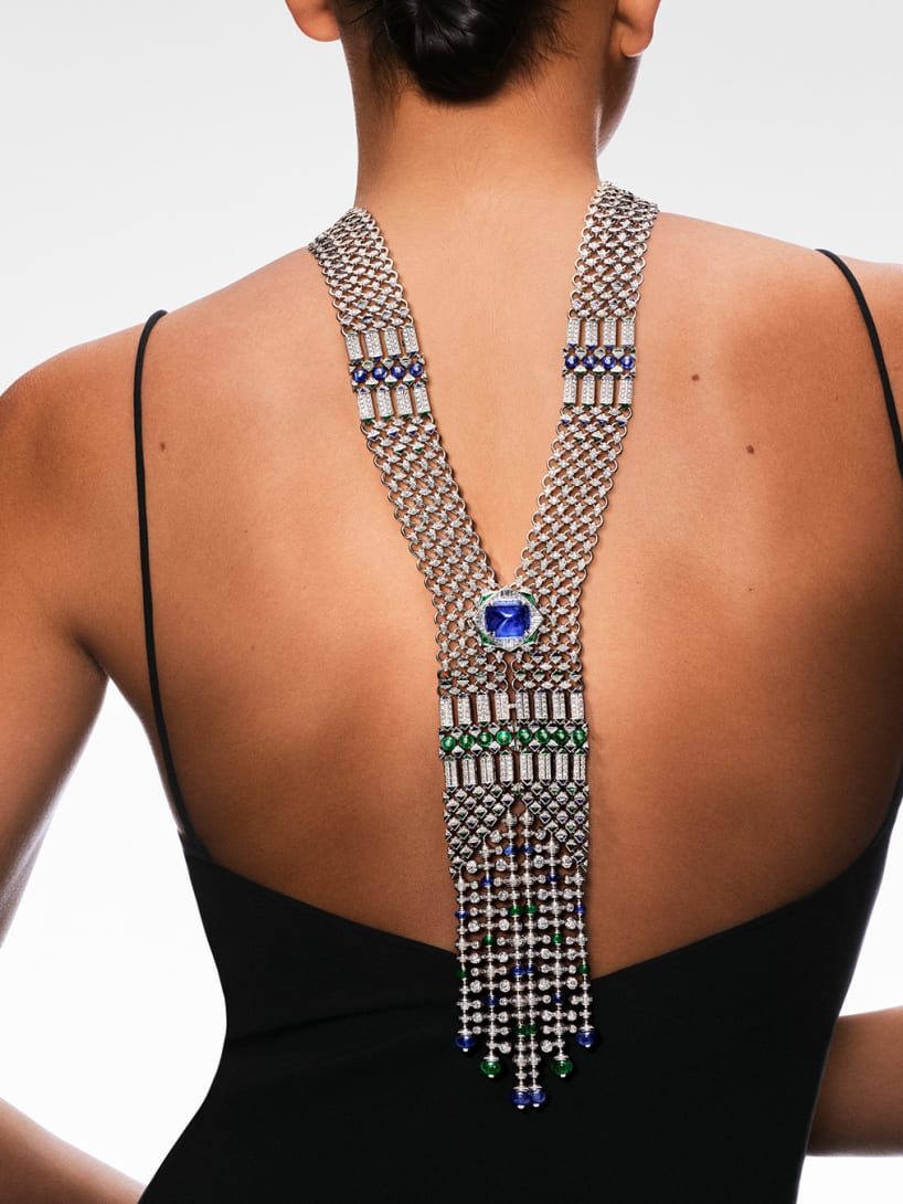 Model from the back wearing a High Jewellery white gold necklace with sapphires, emeralds and diamonds.