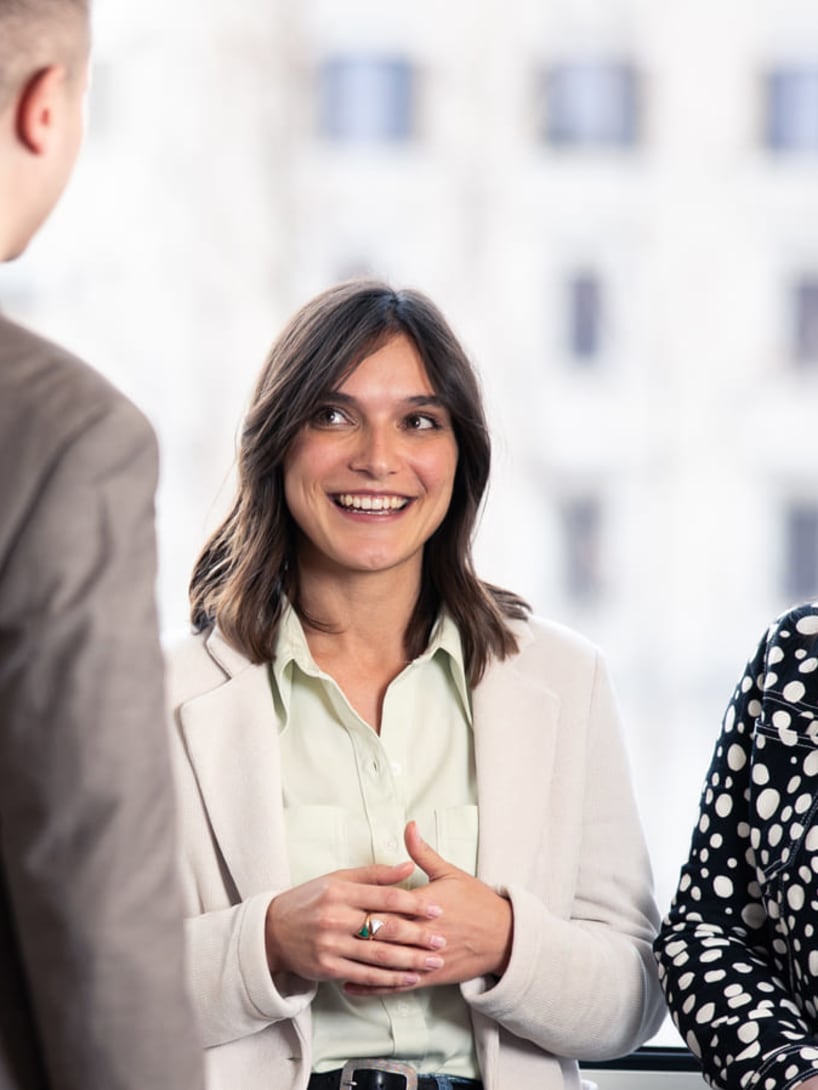 Maria, Internal Communication Manager, parla con alcuni colleghi davanti alla finestra