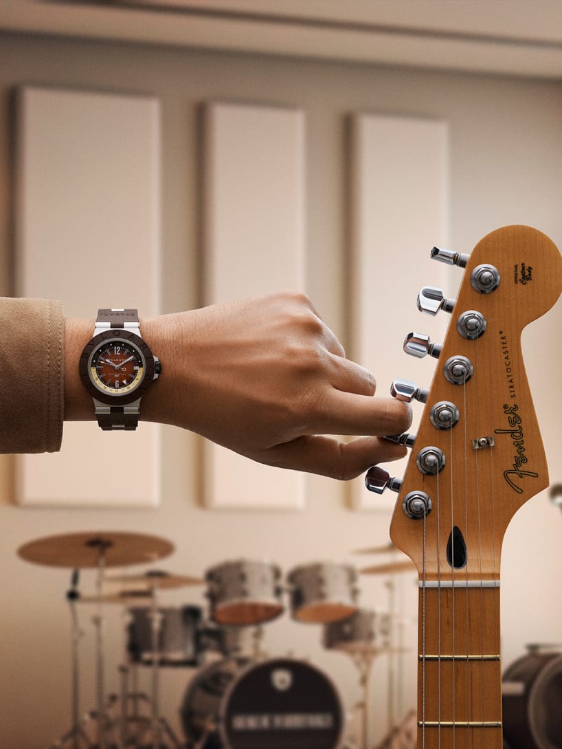 Bvlgari Aluminium GMT x Fender® Limited Edition watch on man's wrist and Stratocaster guitar, close up.