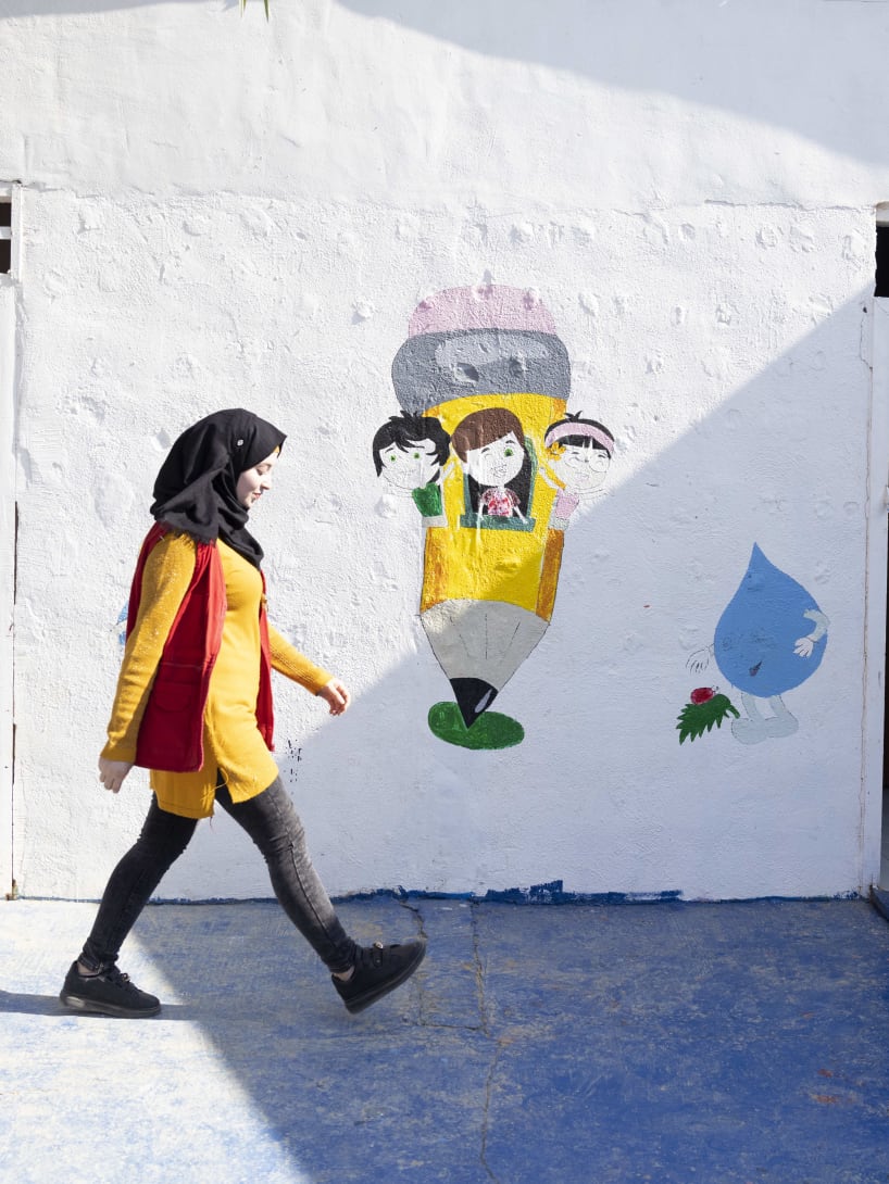 Woman walking in front of an educational centre build by Bvlgari and Save the Children.