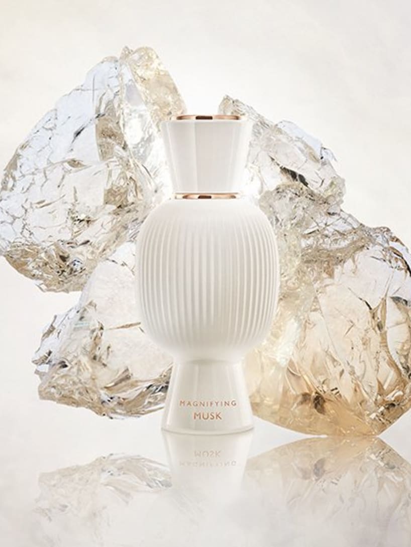 White flacon of the Bvlgari Allegra Magnifying Musk essence in front of white crystals, creative shot.