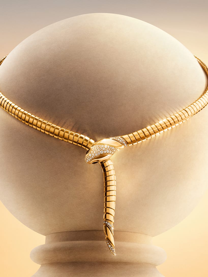 Serpenti Tubogas yellow gold necklace with pavé diamonds, set against a rose-hued sky.