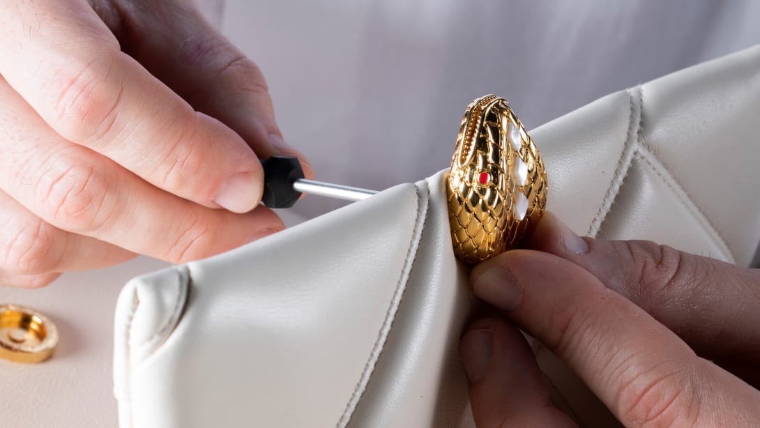 Bulgari artisan assembling the metal snakehead closure on the Serpenti Cabochon calf leather bag.