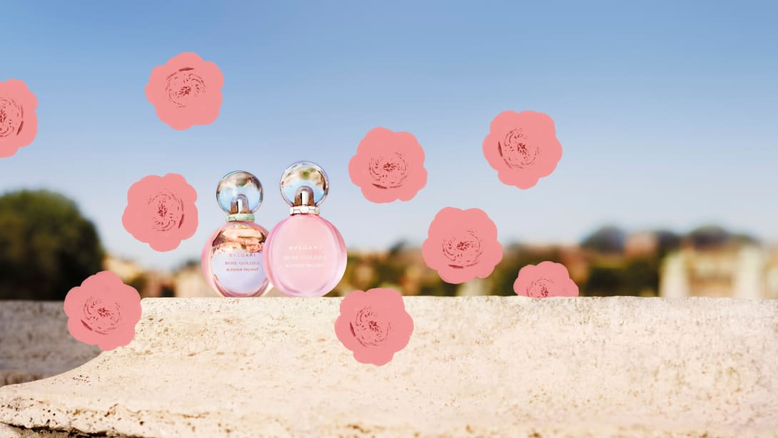Rose Goldea Blossom Delight Eau de Parfum and Eau Toilette, and painted roses, sky backdrop.