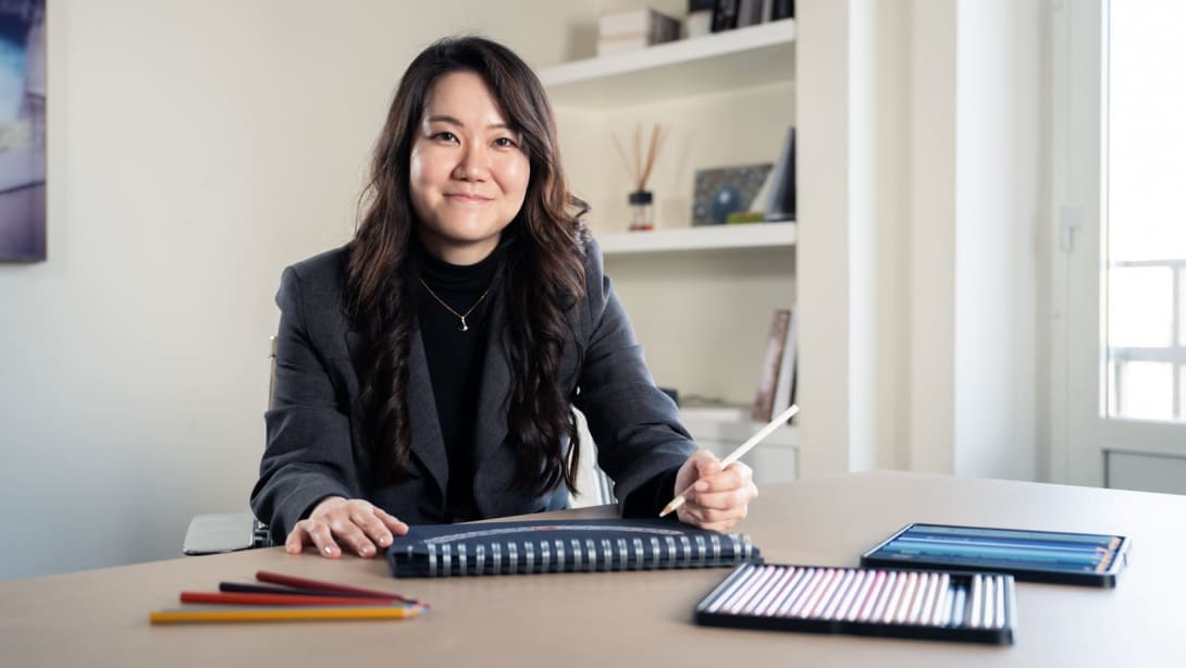 Sun Min, Senior Jewelry Designer, sorride alla fotocamera seduta alla scrivania