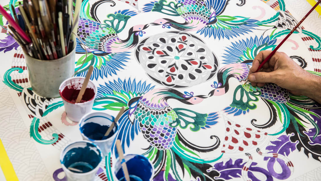 Hand paints a drawing of a Bvlgari Serpenti bag.