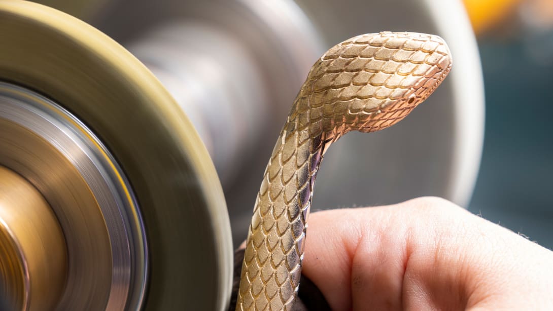 Polishing of a snake body-shaped metallic frame of Bulgari's Serpentine handbags, close up.