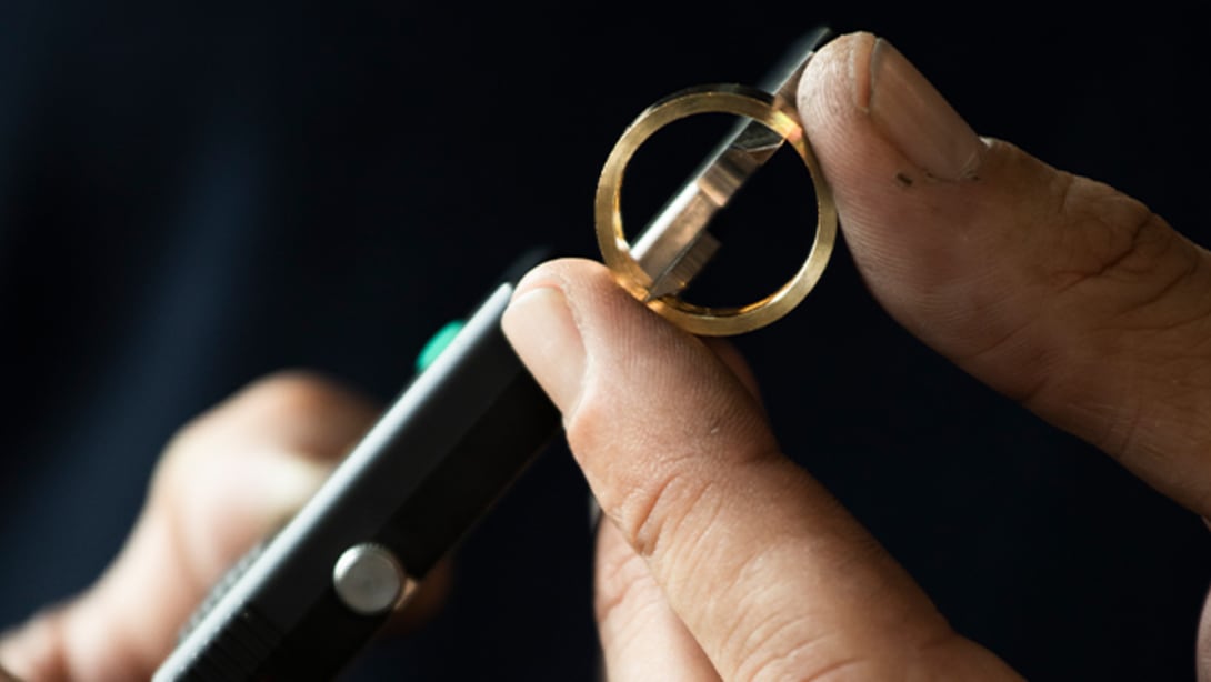 Bulgari artisan checking a gold ring during the making of process, black background, close up shot.