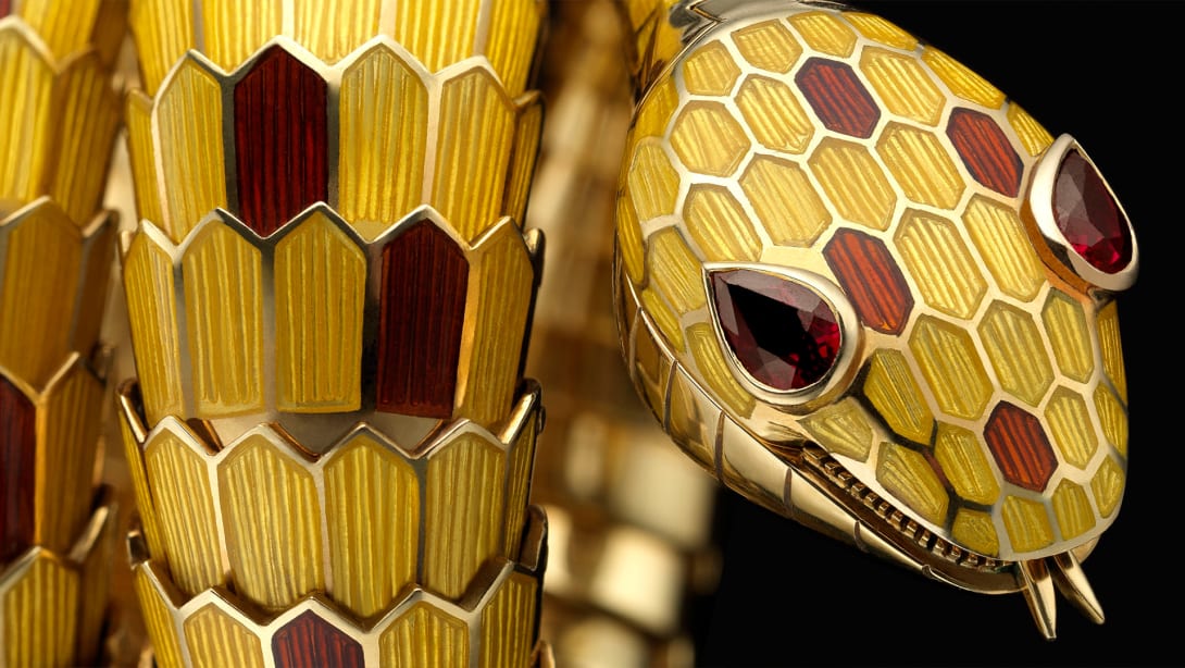 Bulgari Heritage Serpenti secret watch with yellow and brown enamel scales and ruby eyes, close up.