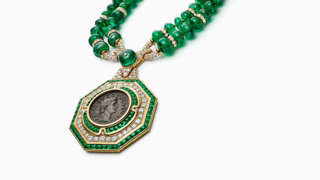 The Augustus Aeternus Emerald Monete High Jewellery sautoir with a rare bronze coin, emeralds and diamonds, close-up.