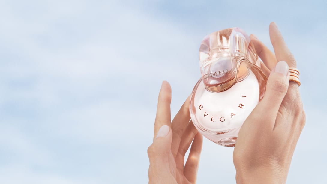 Powder pink transparent bottle of the Omnia Crystalline Eau de Parfum, blue sky in the background