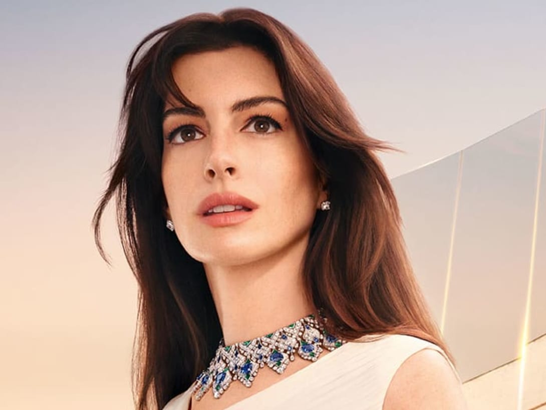 Anne Hathaway wearing a sapphire and diamond High Jewellery necklace, Roman backdrop and the sky at dawn.