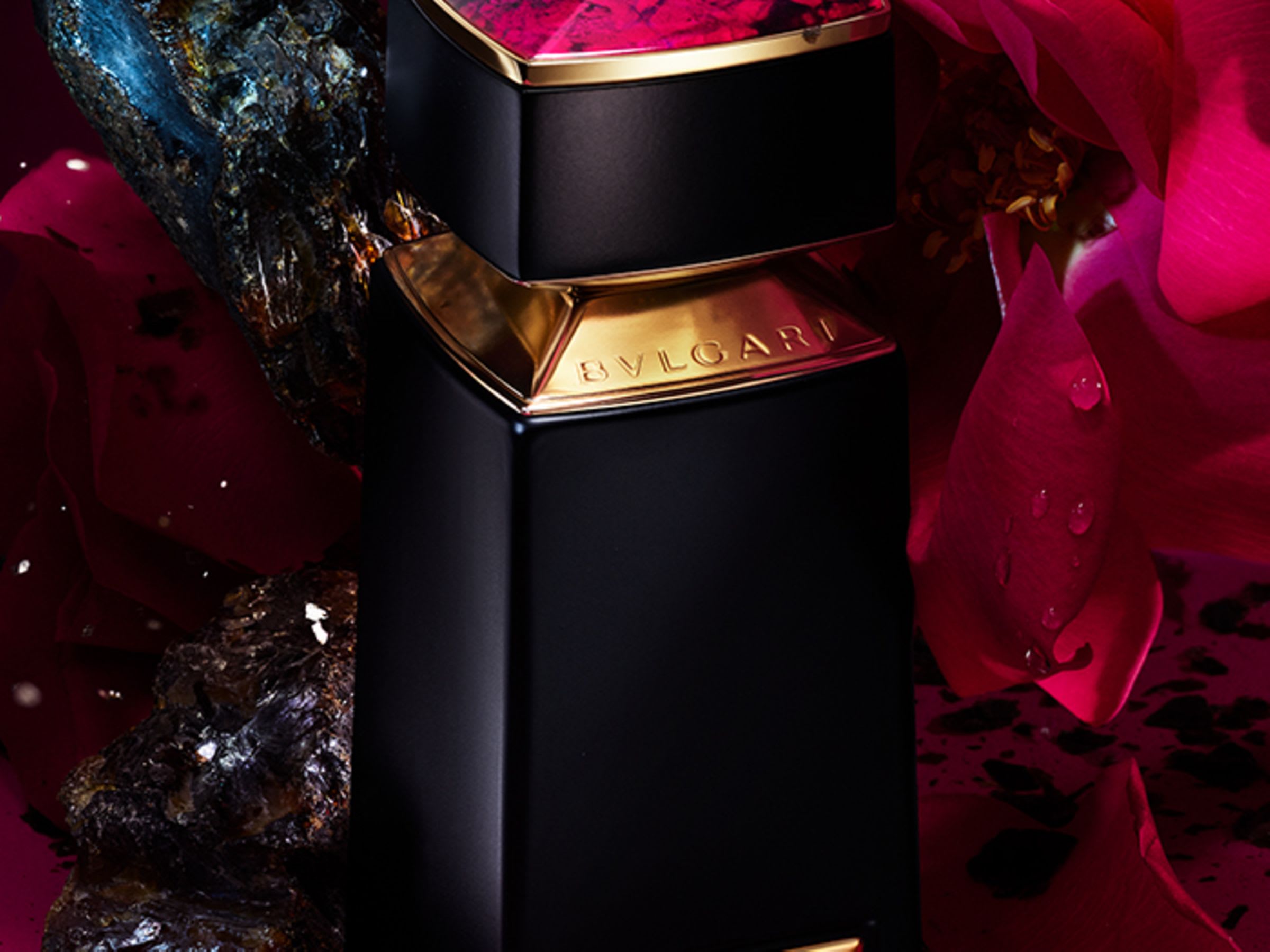 Pink cap of the Bvlgari Le Gemme Sahare fragrance, rose and ambergris in the back, close up.