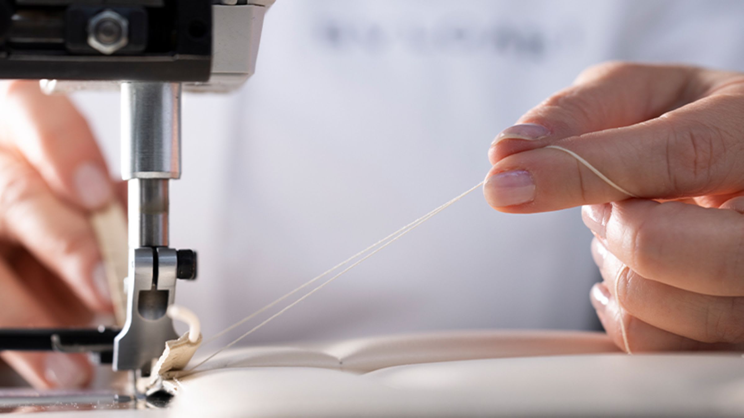Bulgari craftsman sewing the white calf leather panel of a Serpenti handbag, close up.