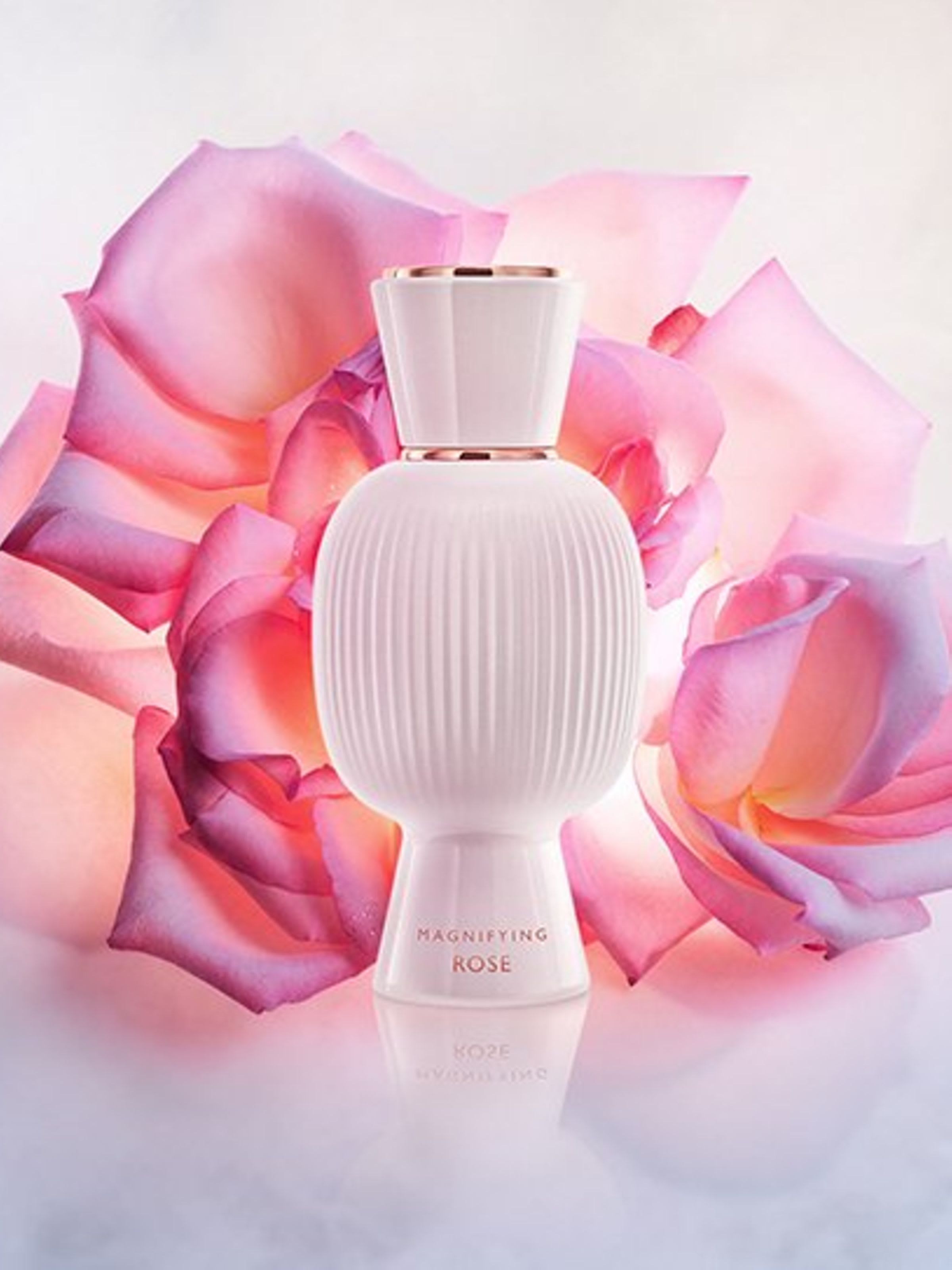 White flacon of the Bvlgari Allegra Magnifying Rose essence in front of a pink rose, creative shot.
