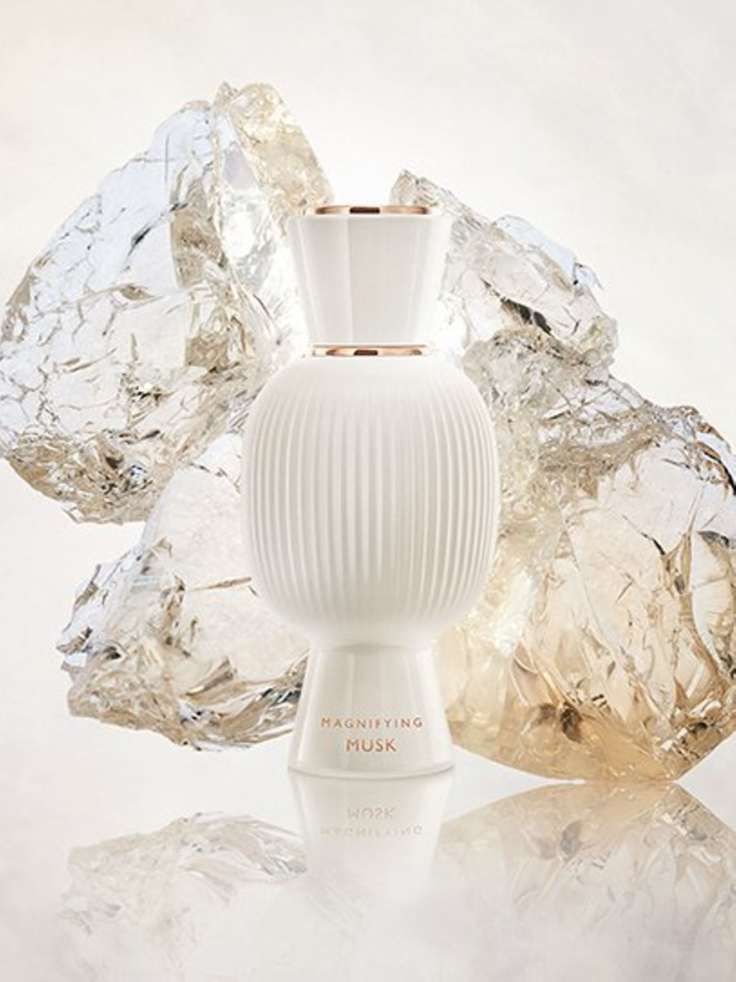 White flacon of the Bvlgari Allegra Magnifying Musk essence in front of white crystals, creative shot.